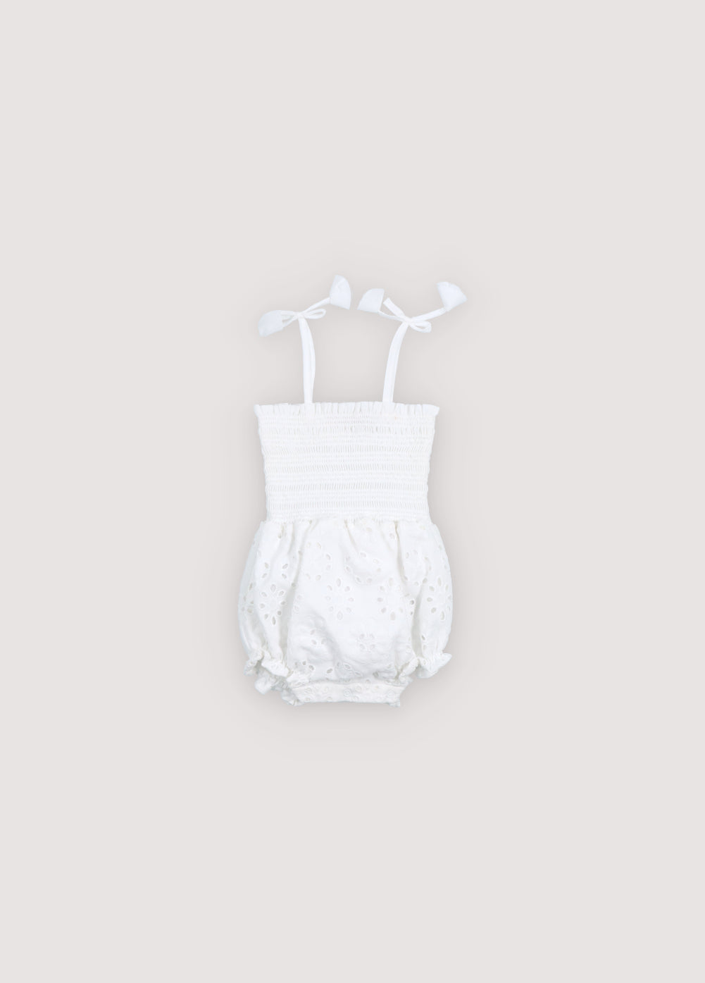 Mameluco para bebé confeccionado con un hermoso algodón bordado con corpiño fruncido y dobladillo con volantes.