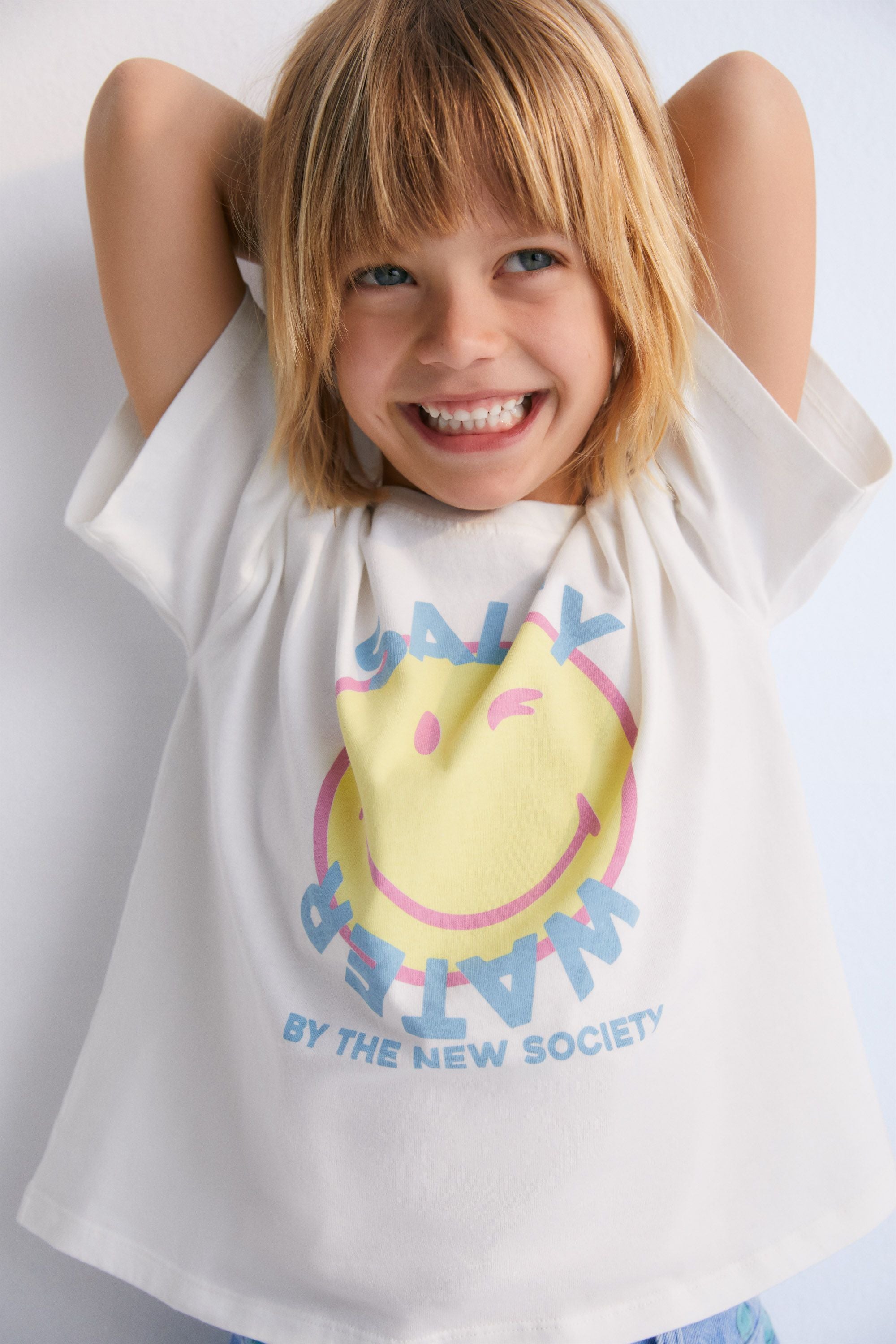 Short-sleeved SMILEY WORLD t-shirt with a colorful print on the front and a patch in matching colors on the sleeve. Spring Summer Collection. The New Society. 