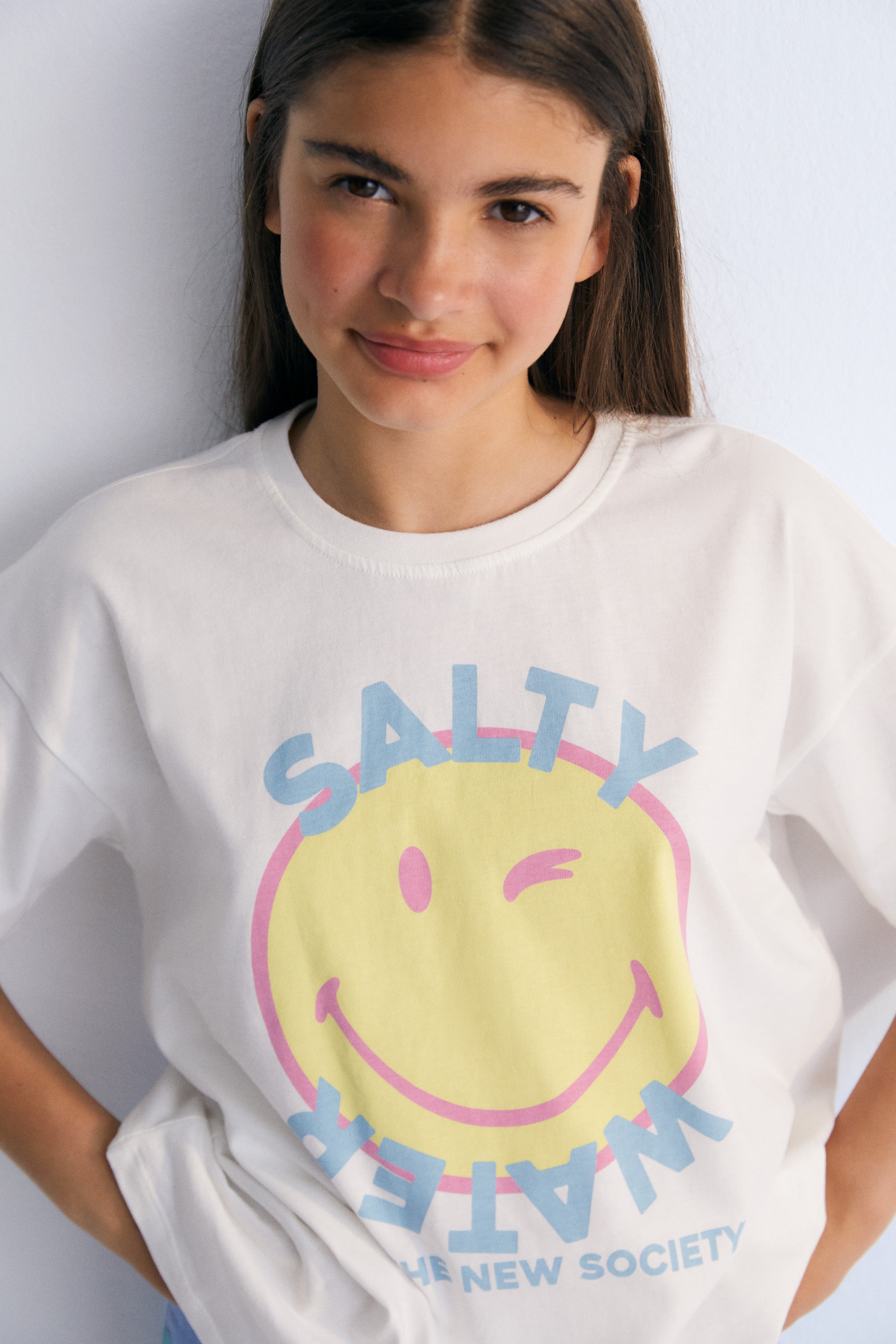 short-sleeved SMILEY WORLD t-shirt with a colorful print on the front and a patch in matching colors on the sleeve. Spring Summer Collection. The New Society.