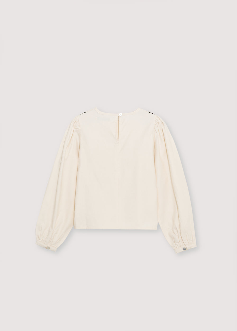 Blouse with a bust cut and gathering detail, featuring delicate contrast embroidery. It has a back opening with a tear and button closure.