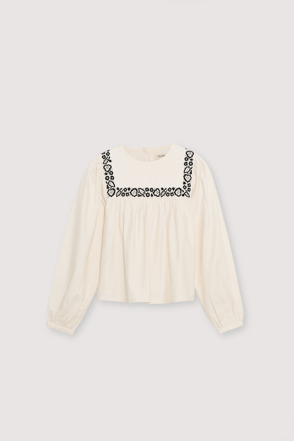 Blouse with a bust cut and gathering detail, featuring delicate contrast embroidery. It has a back opening with a tear and button closure.