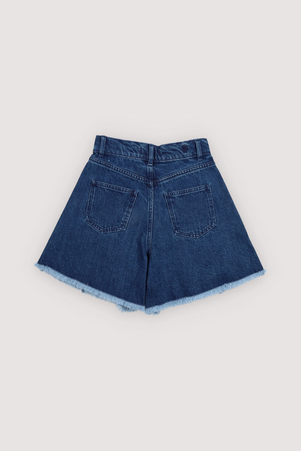 Dark wash denim shorts featuring a&nbsp;side cut for added leg volume, a raw cut hem, and a branded embroidery detail on the back, combining casual style with a playful, modern touch.