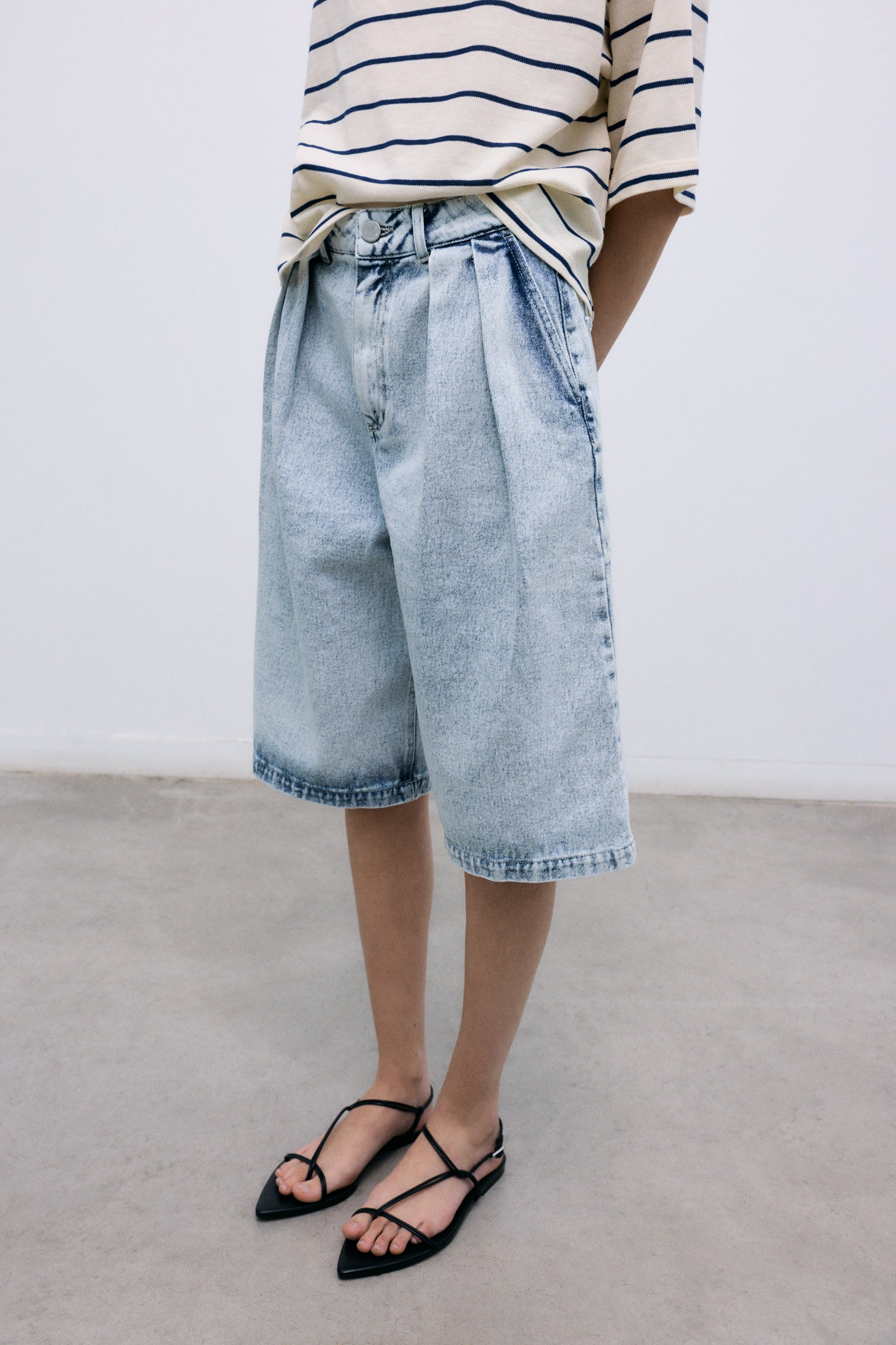 Bleach-wash denim bermuda designed with double front pleats for a structured yet relaxed silhouette.