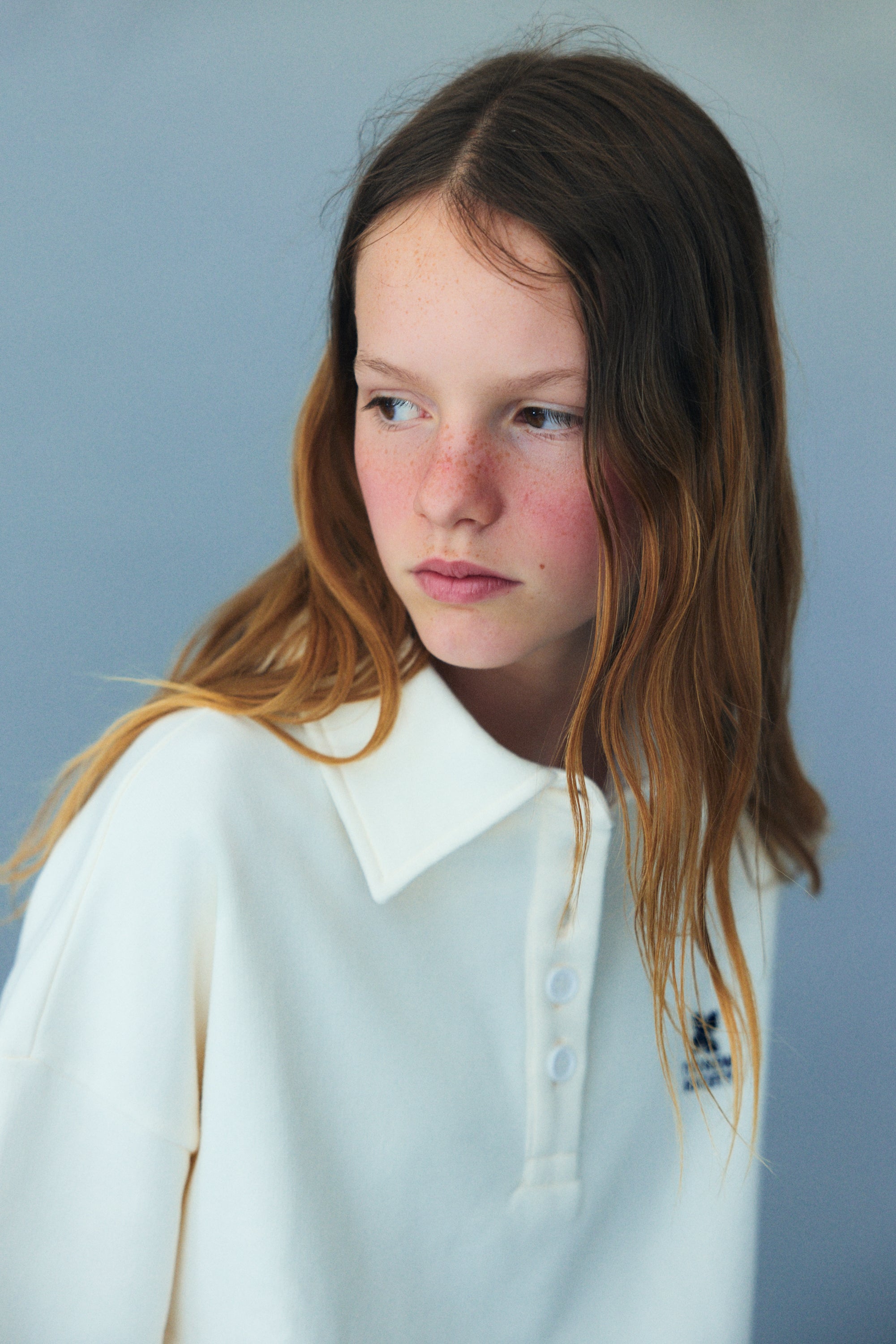 Soft cotton fleece polo featuring ribbed cuffs and hem, a tonal buttoned opening at the neck, and branded embroidery on the chest