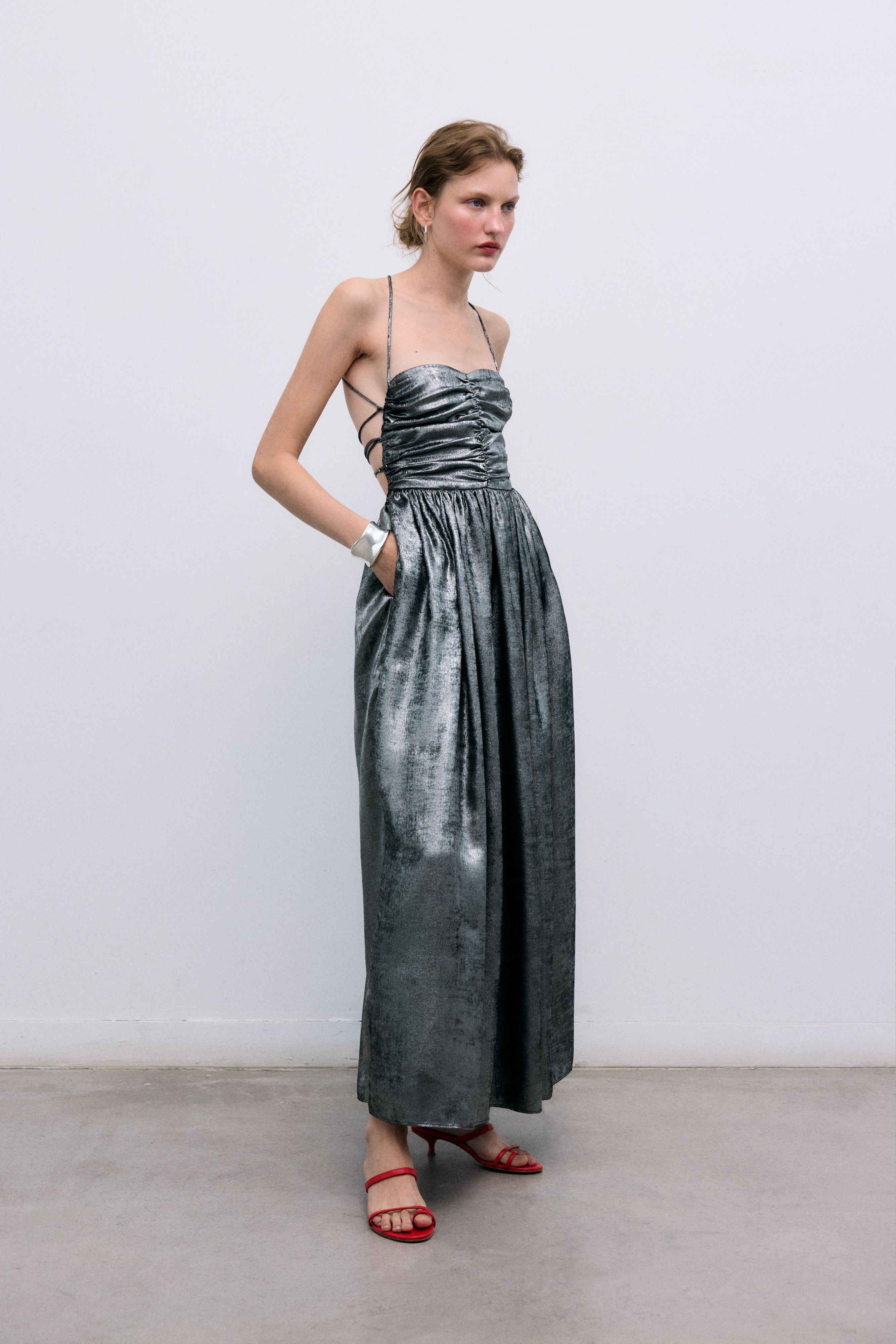 Silver shine dress with a waist cut and front ruching. It features spaghetti straps that cross at the back and a zipper closure.