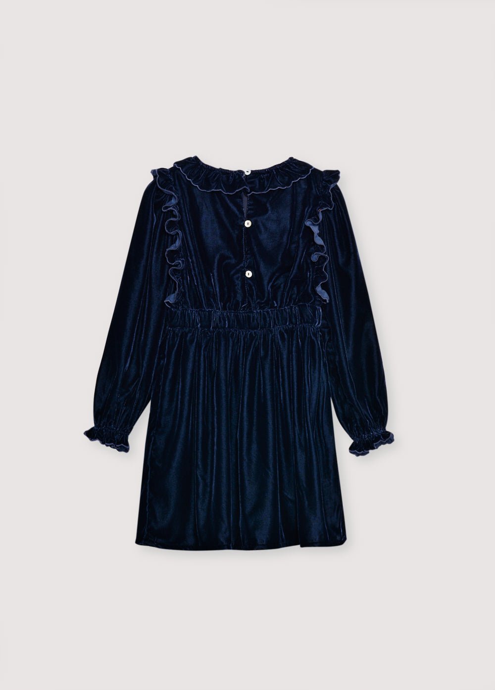Vestido de velour con cintura entallada, detalle de bordado en el pecho y dos bolsillos bordados en la falda. Está rematado con volantes en los puños y se abre en la espalda con detalles de volantes.  El vestido tiene forro de algodón a tono. 