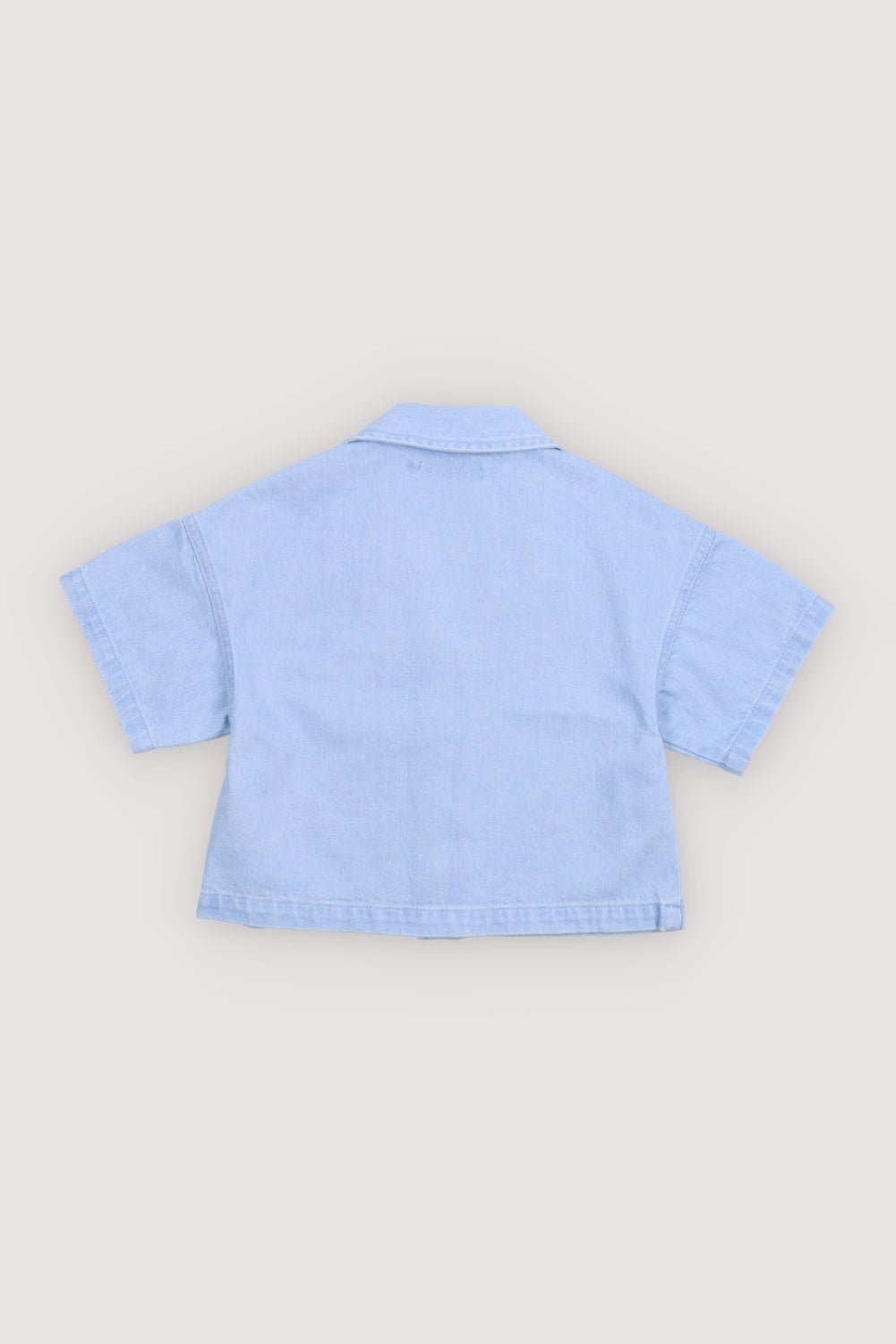 워싱 데님 소재의 반소매 크롭 셔츠. 앞면 스냅 잠금장치, 가슴 포켓, TNS 하트 자수가 특징입니다.