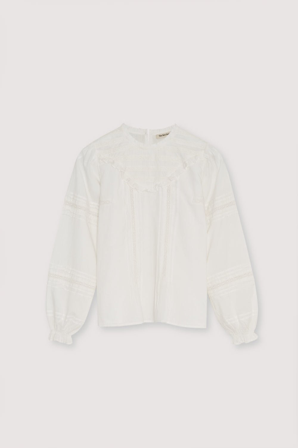 Bluse im romantischen Stil mit einer vorderen Passe aus Spitze und Rüschen sowie Spitzendetails an den Ärmeln. Es verfügt über einen runden Ausschnitt mit einer kleinen Rüschenkante und eine Rückenöffnung mit Knopfverschluss.