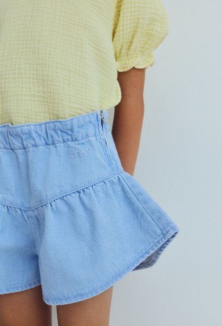Washed denim shorts with a pointed cut and voluminous leg, featuring delicate ruching for a fresh, playful silhouette. 