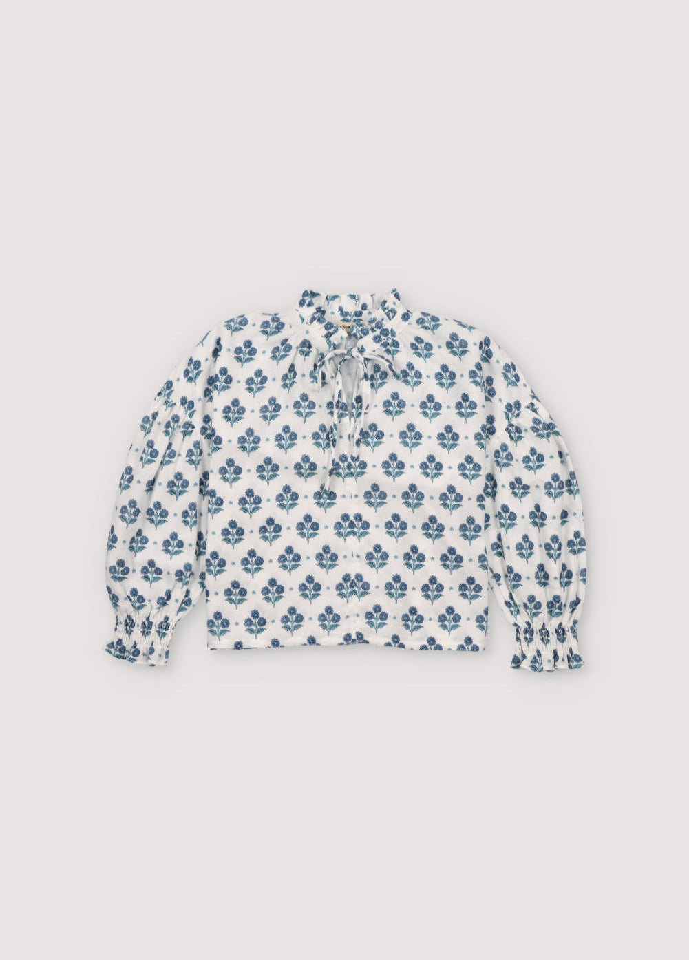 Eleni Blouse in 100% cotton muslin fabric with our hyacinth print. It features a high neckline with a ruffle and adjustable bow, short sleeves with smocking and a decorative ruffle.