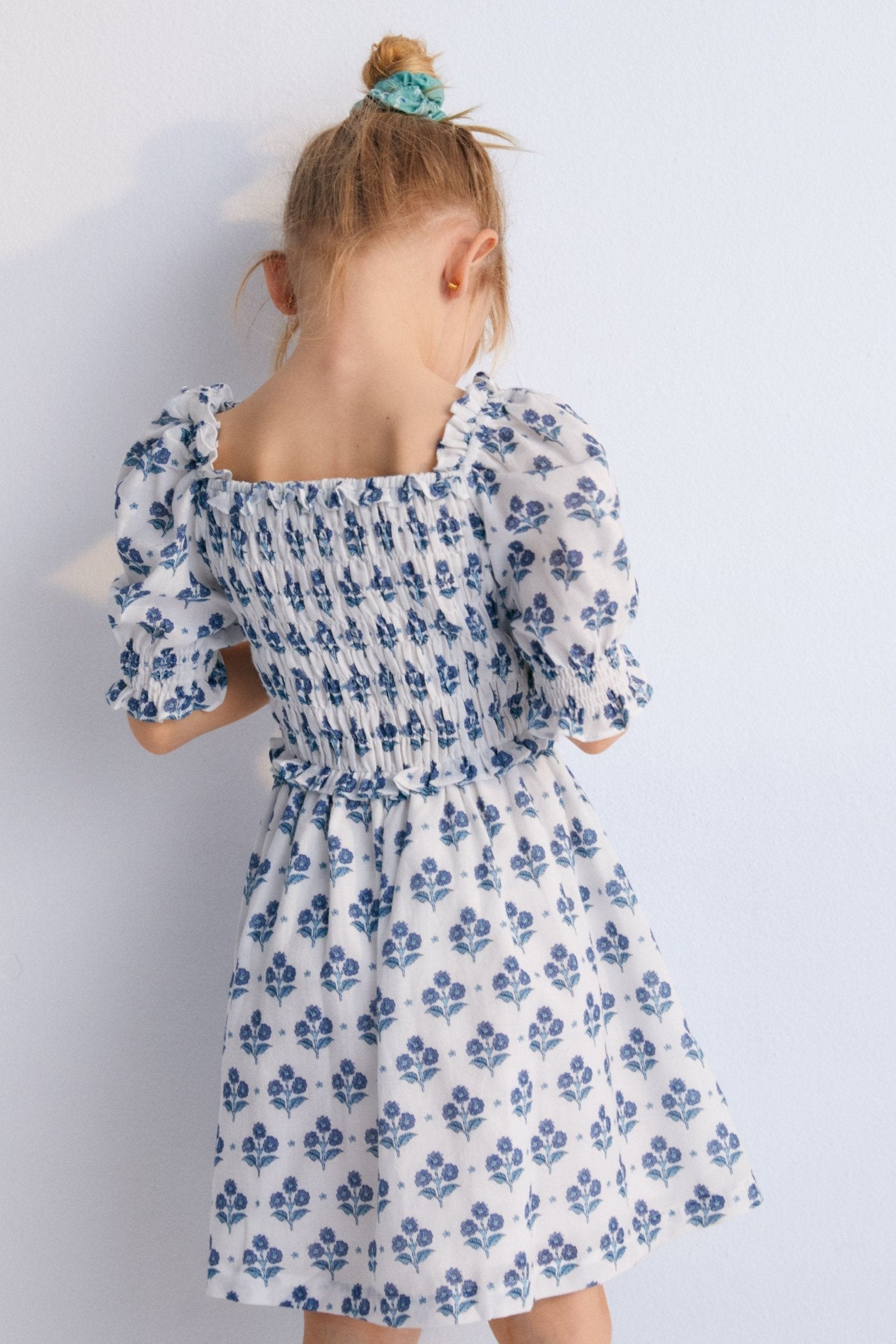 Eleni Dress in 100% cotton muslin fabric with our hyacinth print. The dress features a square neckline with smocking all over, puffed sleeves with smocking and a final ruffle, and a skirt with lots of volume.