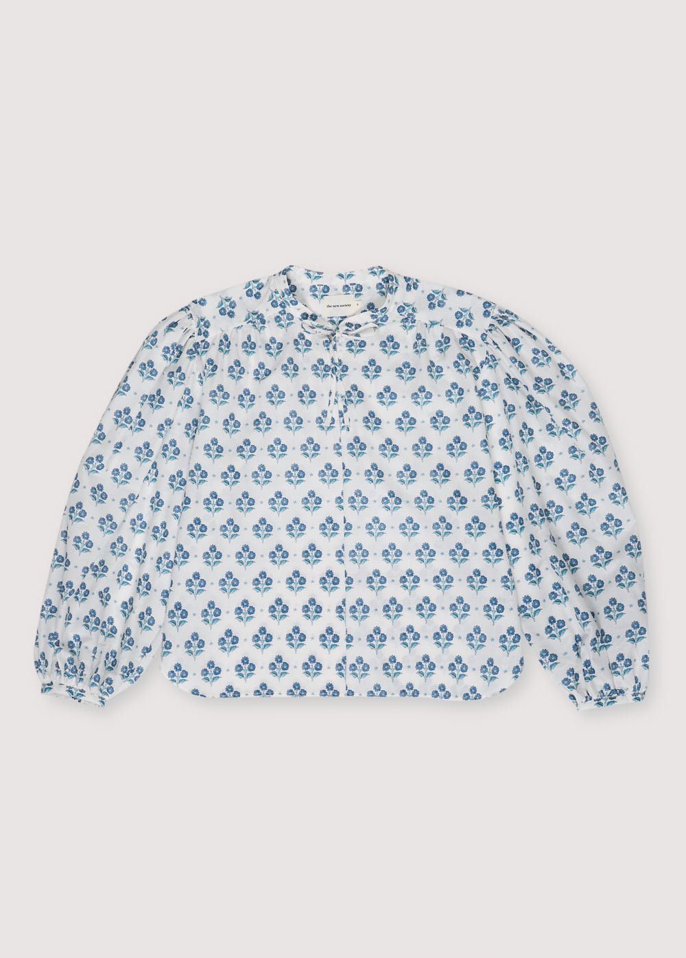 Blusa Mujer Eleni en popelina 100% algodón con nuestro estampado Jacinto. Blusa de manga larga con volante de cuello alto y lazo. Colección Primavera Verano. The New Society.