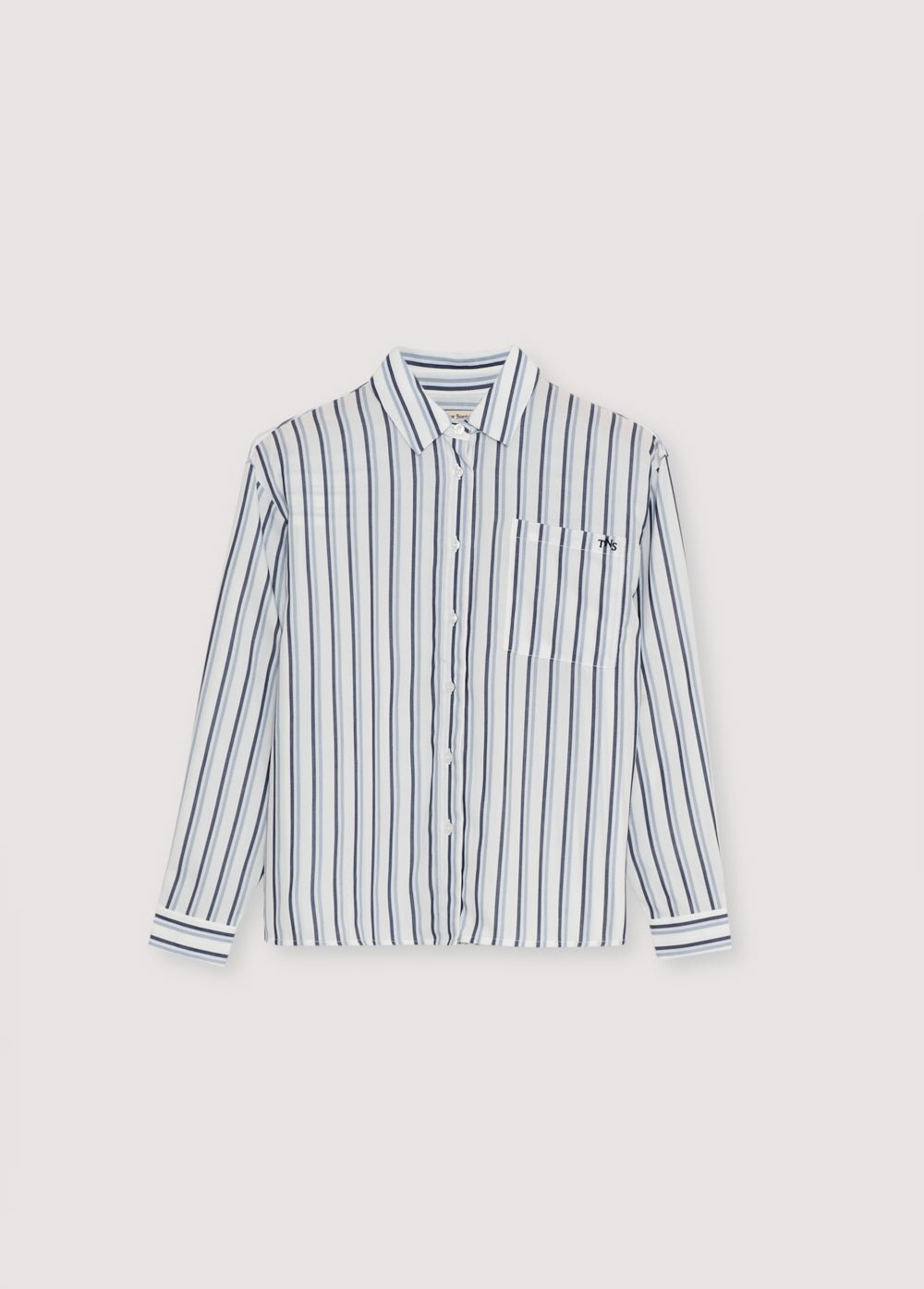 Camisa de rayas tencel en tonos azulados con puños y abertura con botones en el mismo tono. Tiene un bolsillo de parche en la parte delantera. Tiene una bufanda a juego de la misma calidad.