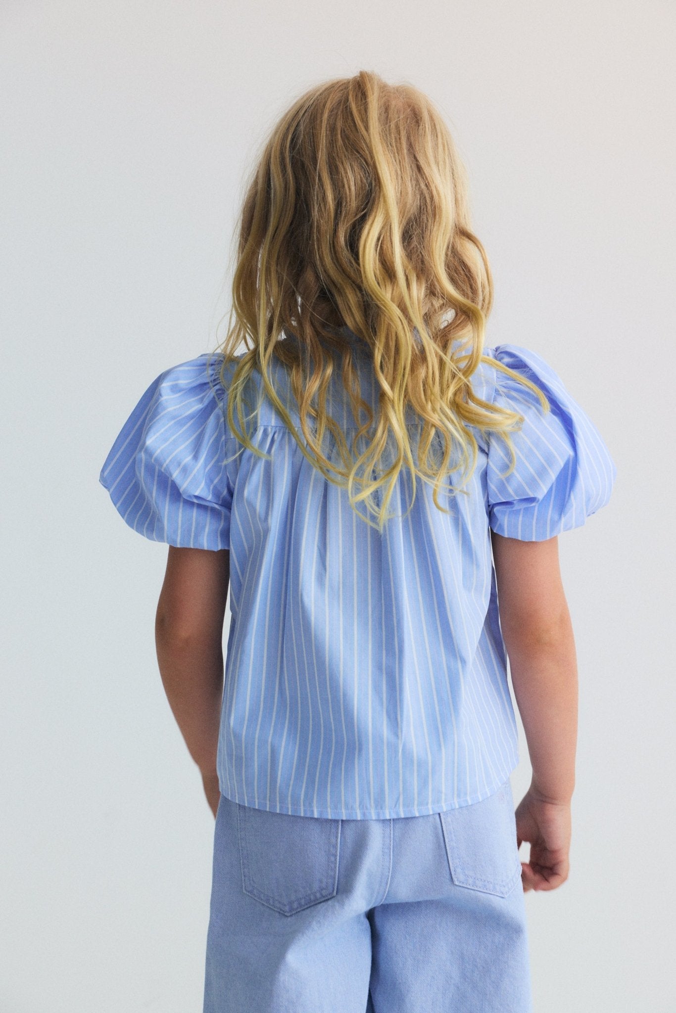 Blue striped blouse featuring a beautiful smocked front with button opening and original puff sleeves, making it a truly special and feminine piece.