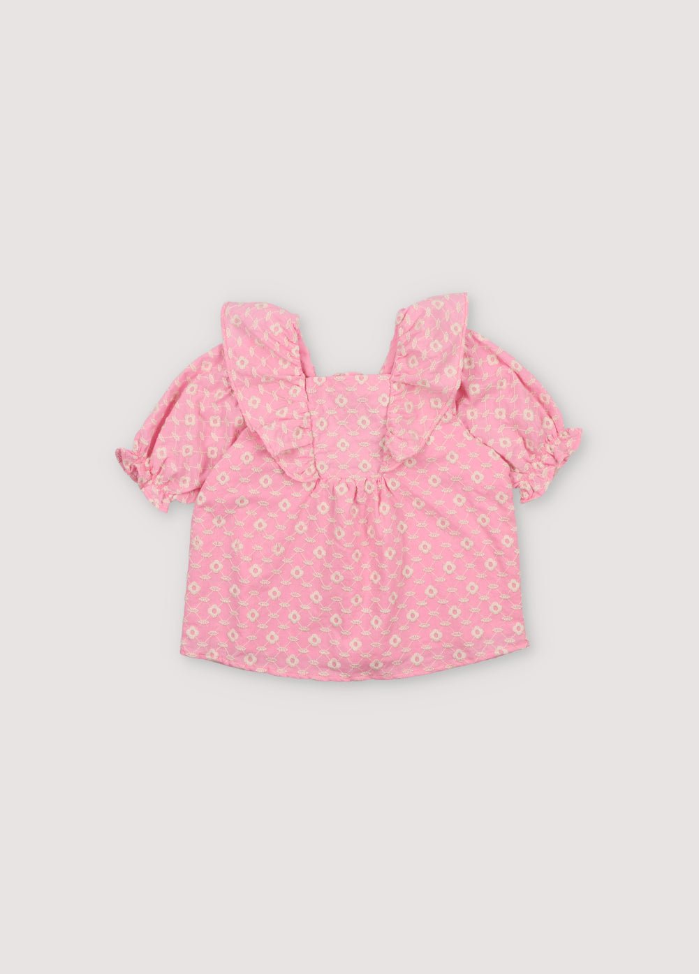 Isidora Blouse in hibiscus voile fabric with macadamia cot-pes embroidery. Square neckline, side ruffles, and puffed short sleeves.
