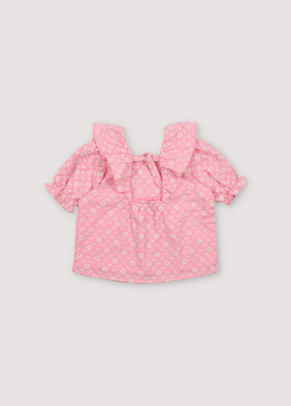 Isidora Blouse in hibiscus voile fabric with macadamia cot-pes embroidery. Square neckline, side ruffles, and puffed short sleeves.
