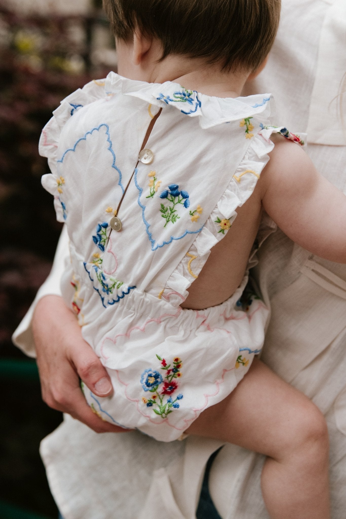 Baby romper crafted from 100% cotton, featuring a special and delicate all-over multicolor floral embroidery.