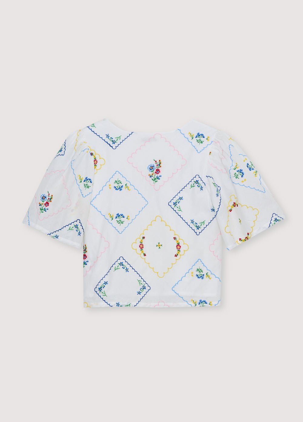 Delicada y encantadora, esta blusa 100% algodón, confeccionada en Portugal, presenta un exquisito bordado floral multicolor en toda su extensión.