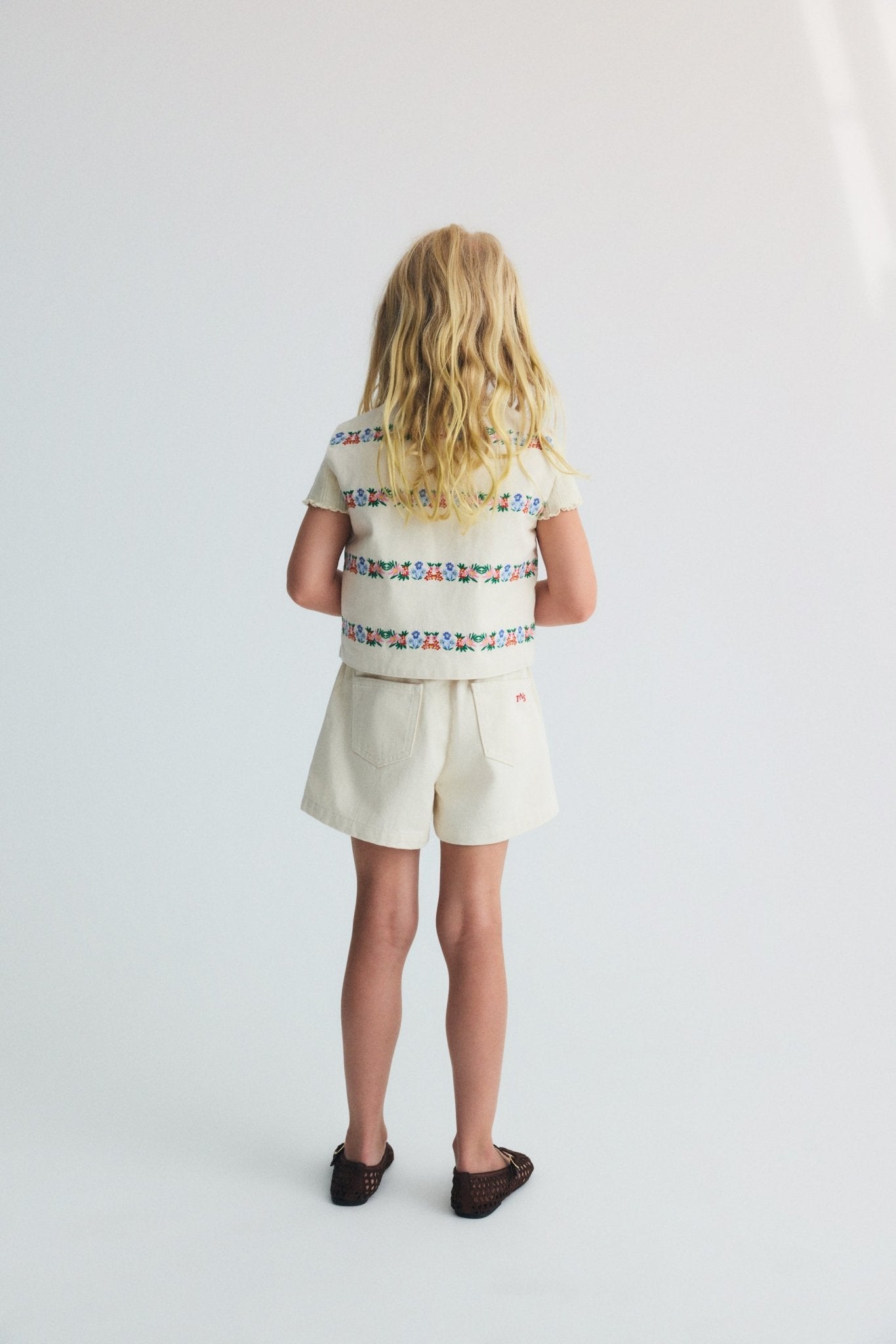 Steppweste für Kinder aus BCI-Baumwolldenim mit zarten und schönen Stickereidetails auf der Vorder- und Rückseite.