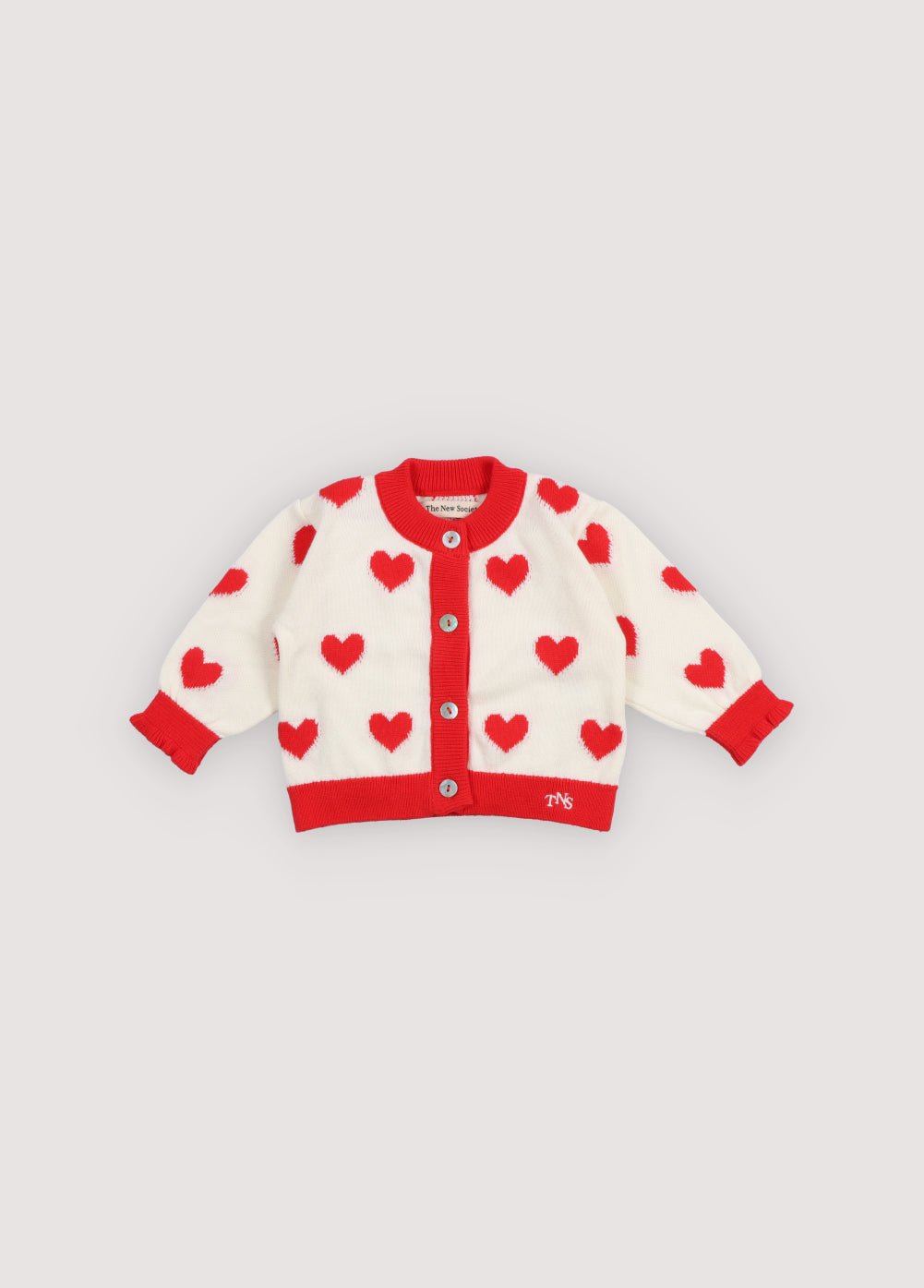 Fine cotton knit cardigan featuring playful contrasting red hearts, contrasting rib trims, and a delicate mother of pearl button closure for a charming, stylish look.