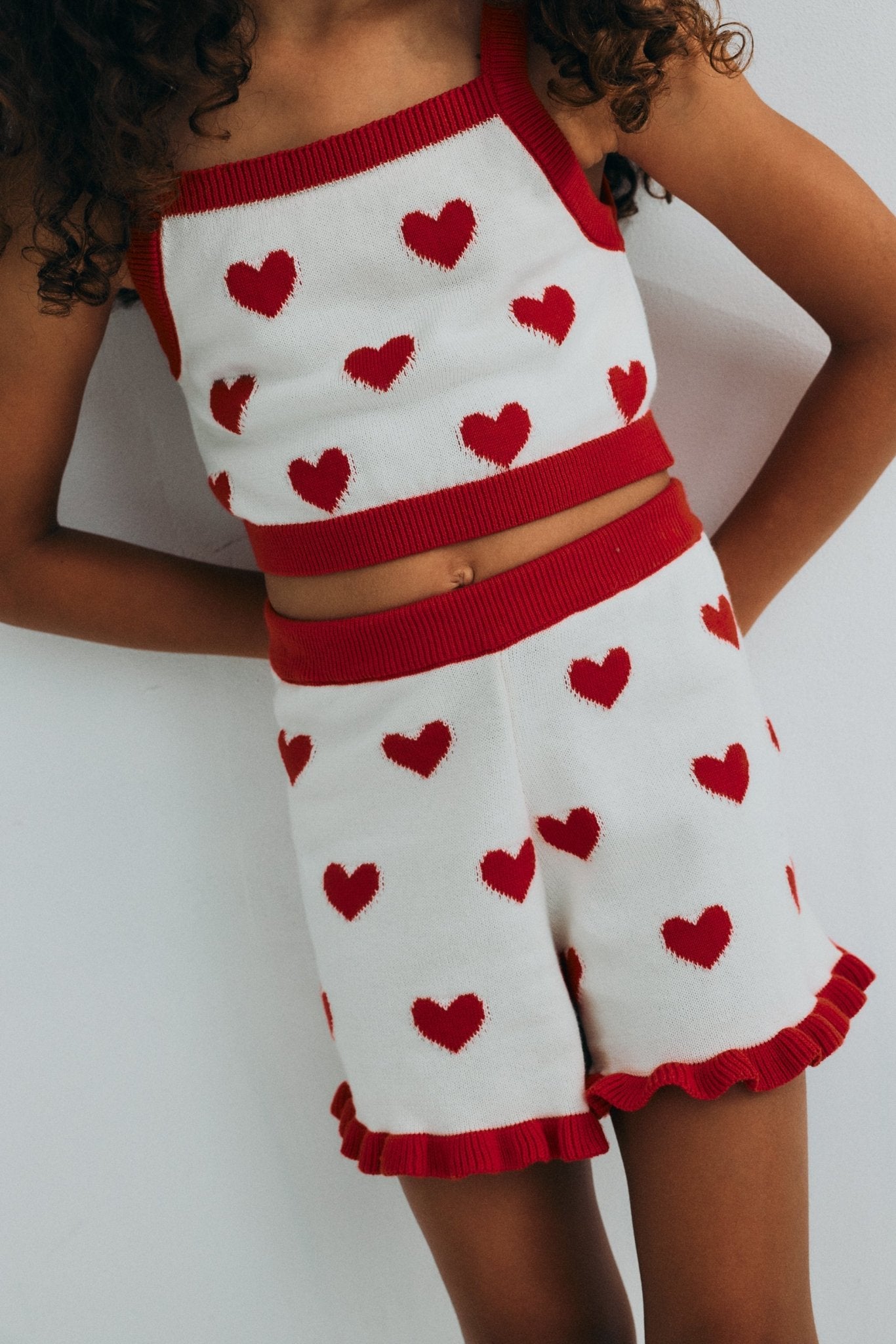 Fine cotton knit shorts featuring a playful heart jacquard, a contrasting ruffle hem, and a comfortable elastic rib waistband for a cute, coordinated summer look.