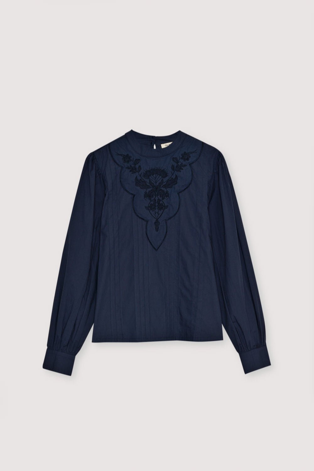 Blouse en popeline avec détail brodé et plis sur le devant. Il présente des poignets boutonnés et des manches froncées aux épaules. Le chemisier s'ouvre dans le dos par une goutte d'eau et un bouton.