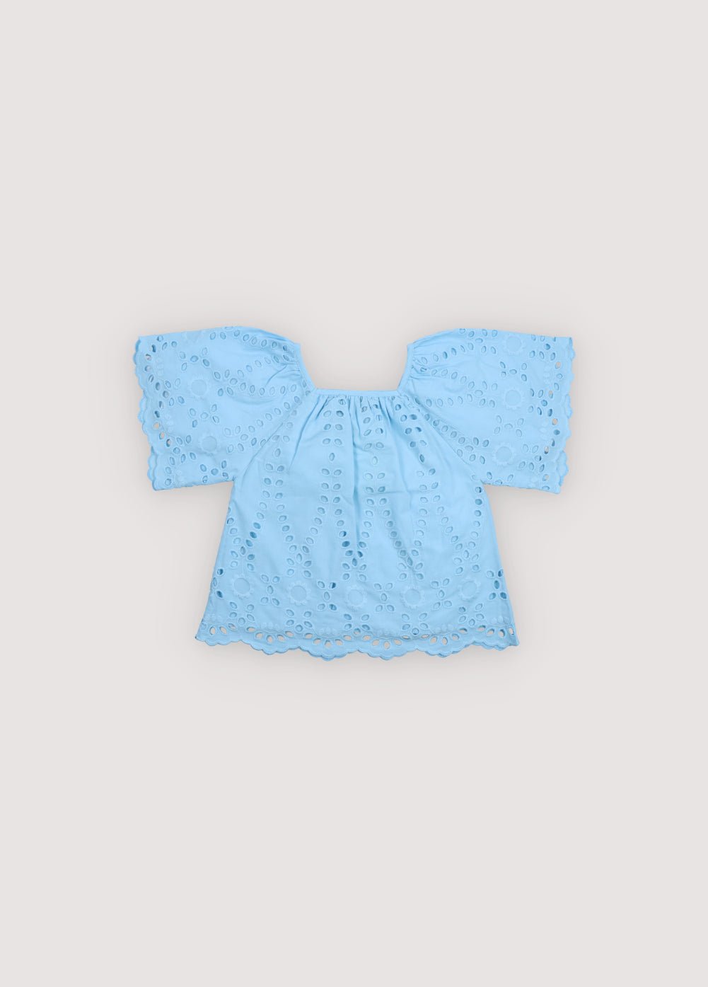 Patmos Blouse in embroidered voile fabric, 100% cotton, in powder blue color, featuring wide sleeves, gathers at the shoulders, front, and back for added volume, and embroidered fabric finishing on the sleeve cuffs and blouse hem. Spring Summer Collection. The New Society. 