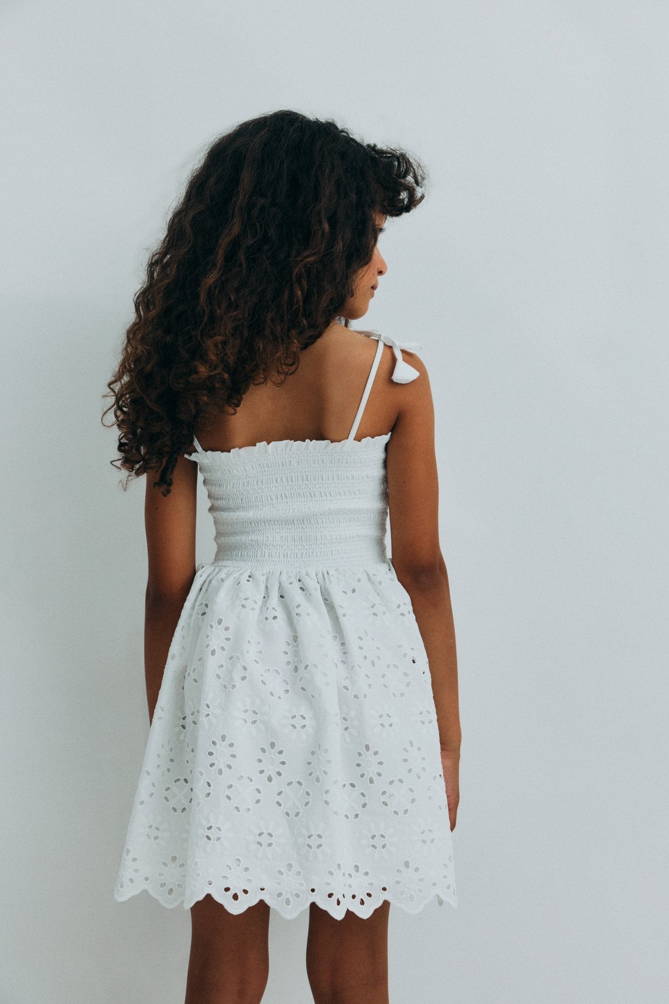 Short dress in beautiful embroidered cotton fabric, featuring a smocked bodice with ruffle detail for a comfortable and flattering fit.