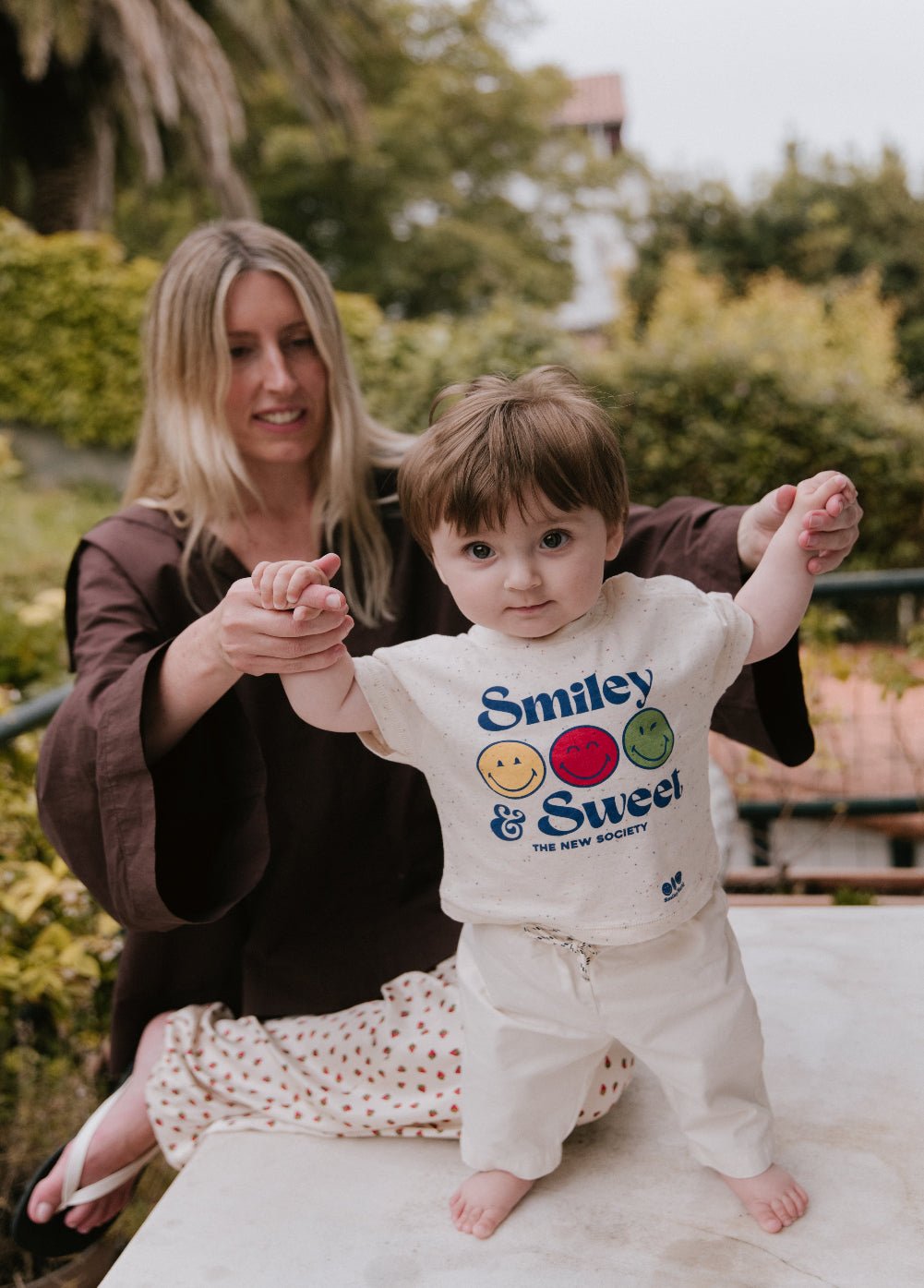 楽しいまだら模様のジャージー T シャツ。前面に SmileyWorld® プリントが施され、肩のスナップボタンで簡単に着用でき、遊び心と実用性を加えています。