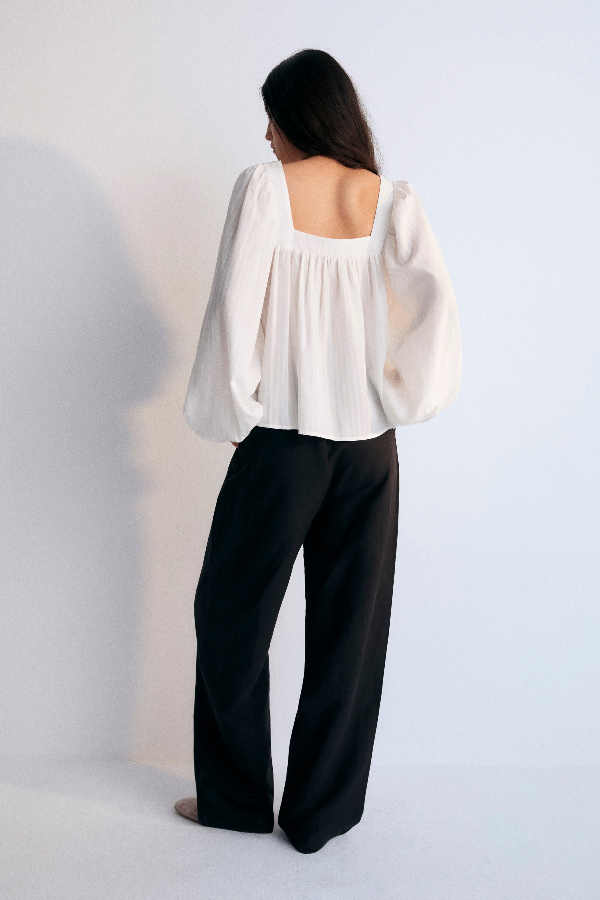 Blouse in crisp white is crafted from 100% Tencel striped fabric, offering a light and breathable feel. The square neckline adds a contemporary touch, while the gathered details create a flattering volume.