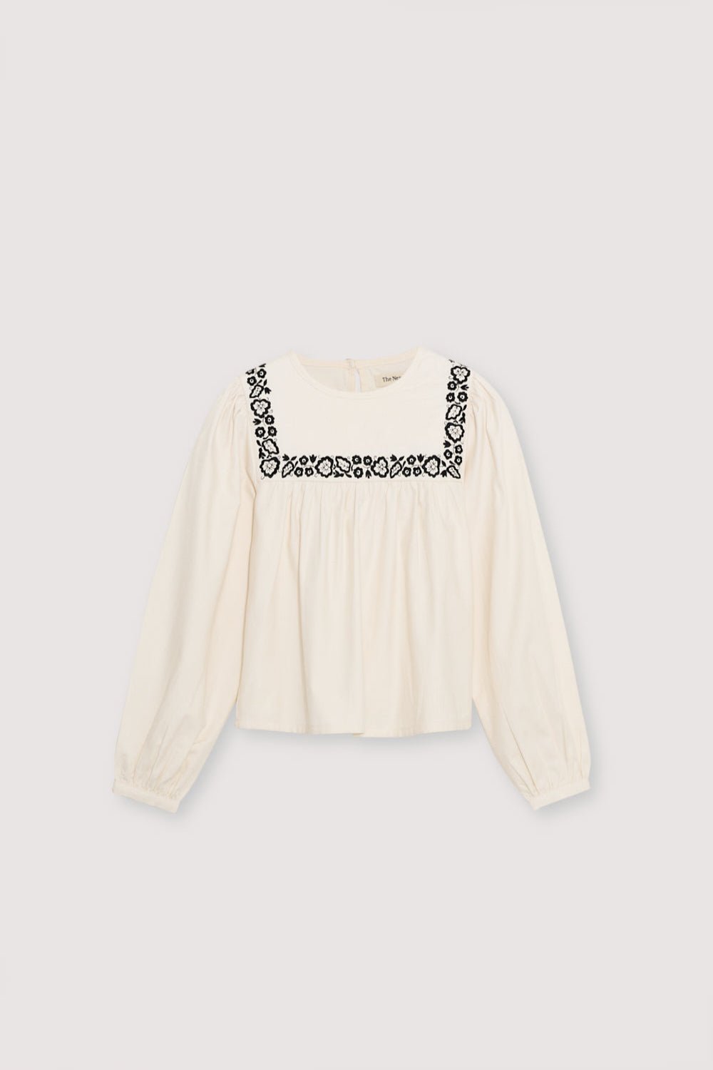 Blouse with a bust cut and gathering detail, featuring delicate contrast embroidery. It has a back opening with a tear and button closure.