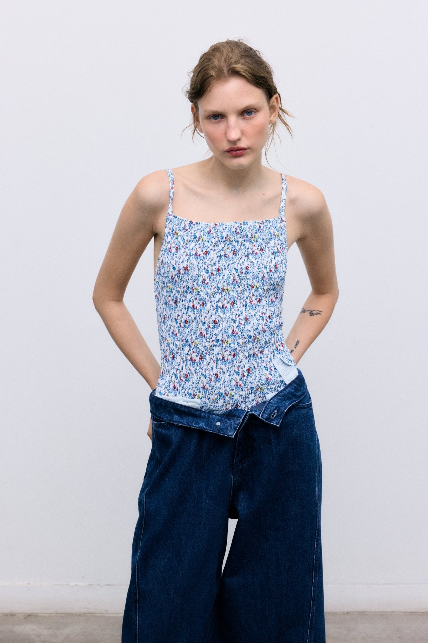 Pantalón de mezclilla con lavado oscuro y corte extra ancho y relajado. Diseñado con bolsillos delanteros y traseros, cortes de costuras laterales que añaden volumen a la pierna y un detalle bordado de la marca en la cintura trasera para un acabado distintivo.