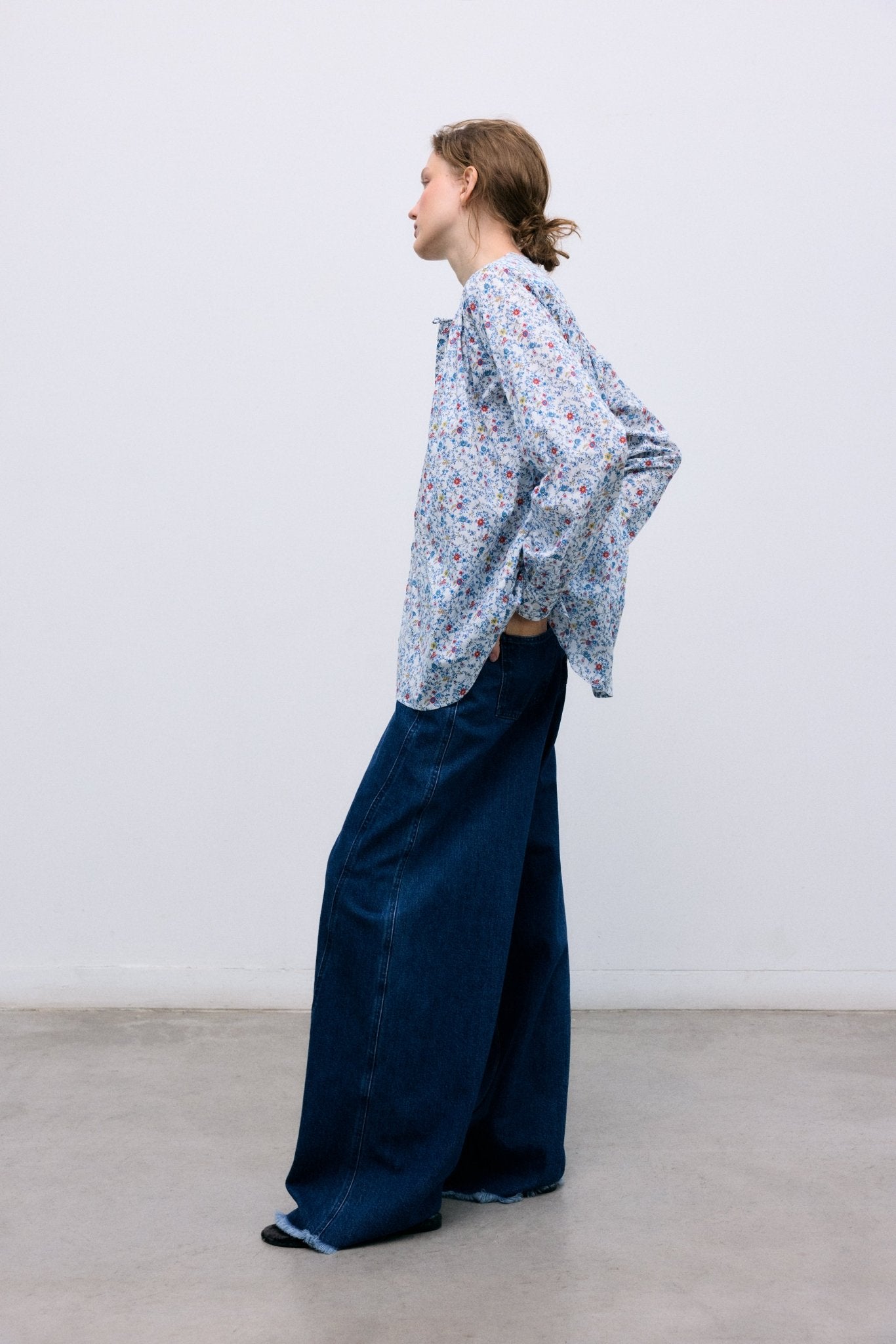 Dark wash denim pants with an extra-wide, relaxed fit. Designed with front and back pockets, side seam cuts that add volume to the leg, and a branded embroidery detail on the back waistband for a distinctive finish.