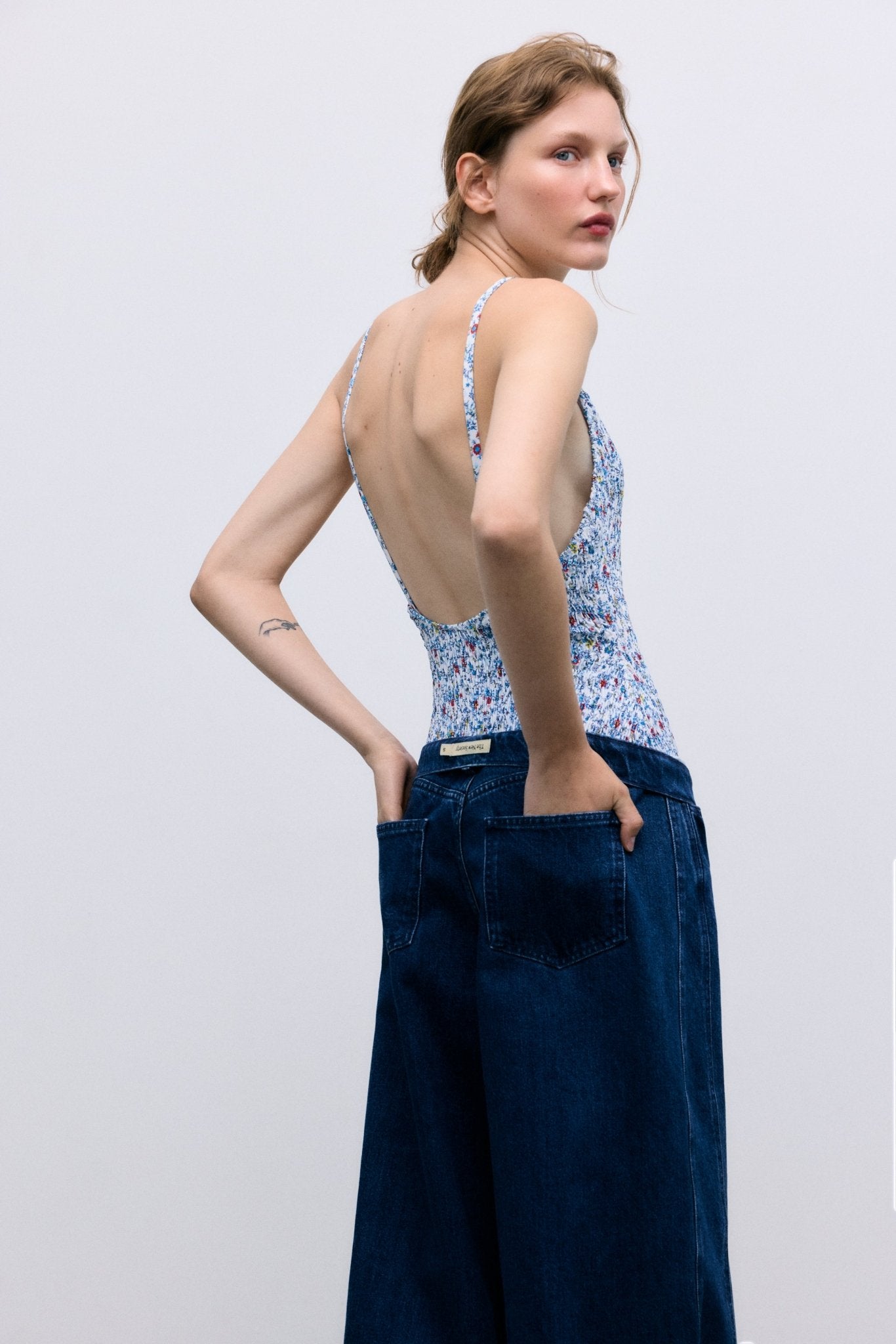 Pantalón de mezclilla con lavado oscuro y corte extra ancho y relajado. Diseñado con bolsillos delanteros y traseros, cortes de costuras laterales que añaden volumen a la pierna y un detalle bordado de la marca en la cintura trasera para un acabado distintivo.