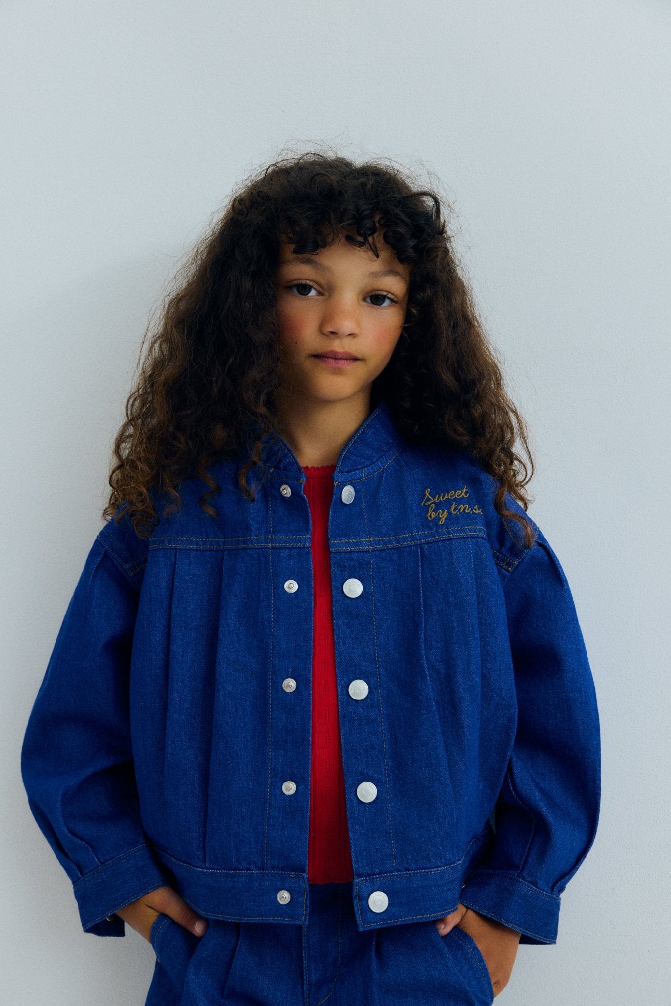 Veste en jean avec détails plissés sur le devant et dans le dos, empiècement et poches, créant une silhouette structurée mais décontractée.