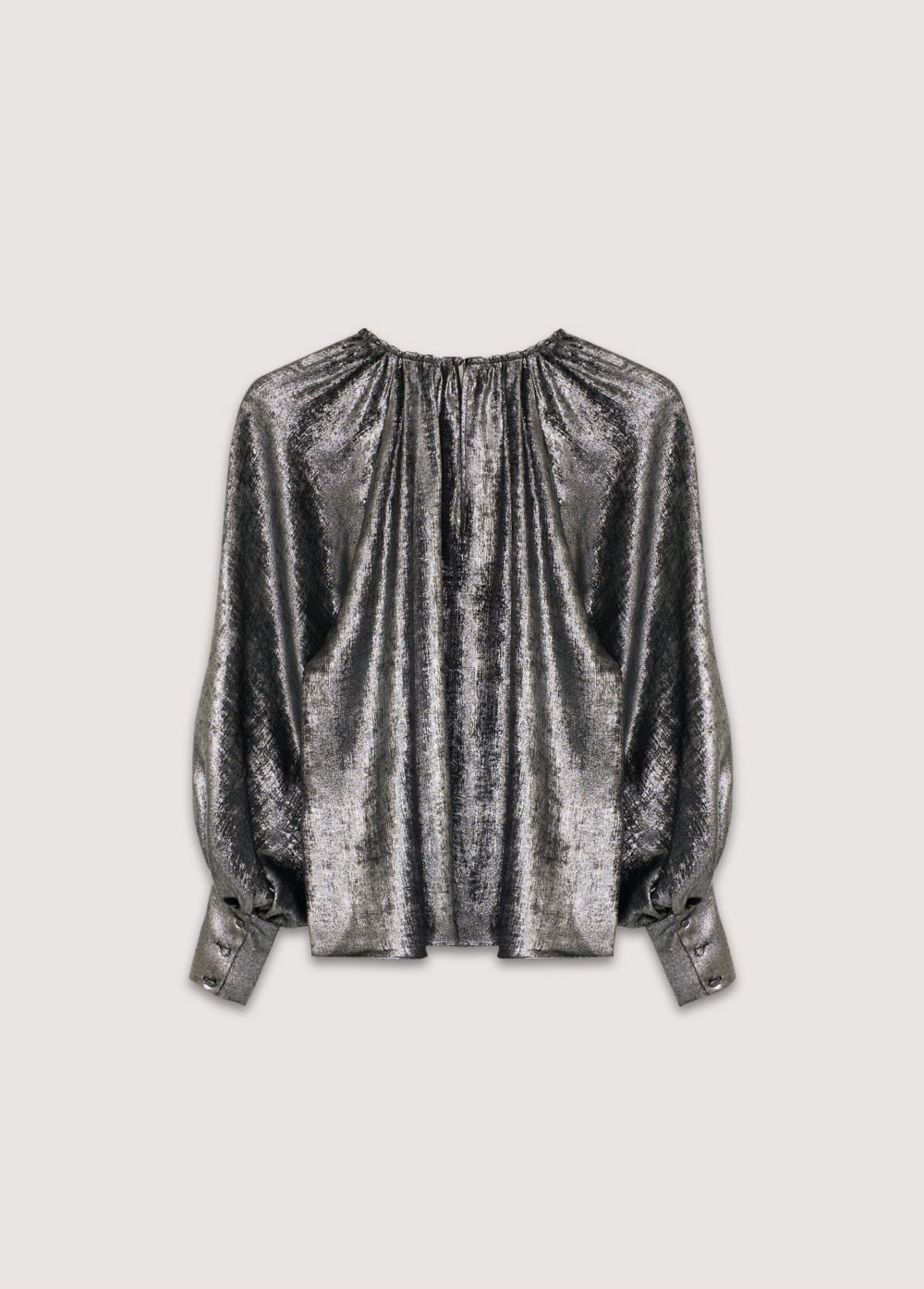 Blouse argentée brillante à encolure ronde et détails froncés, manches bouffantes à larges poignets et boutons recouverts du même tissu. Il présente une ouverture arrière avec un trou de serrure et une fermeture boutonnée.