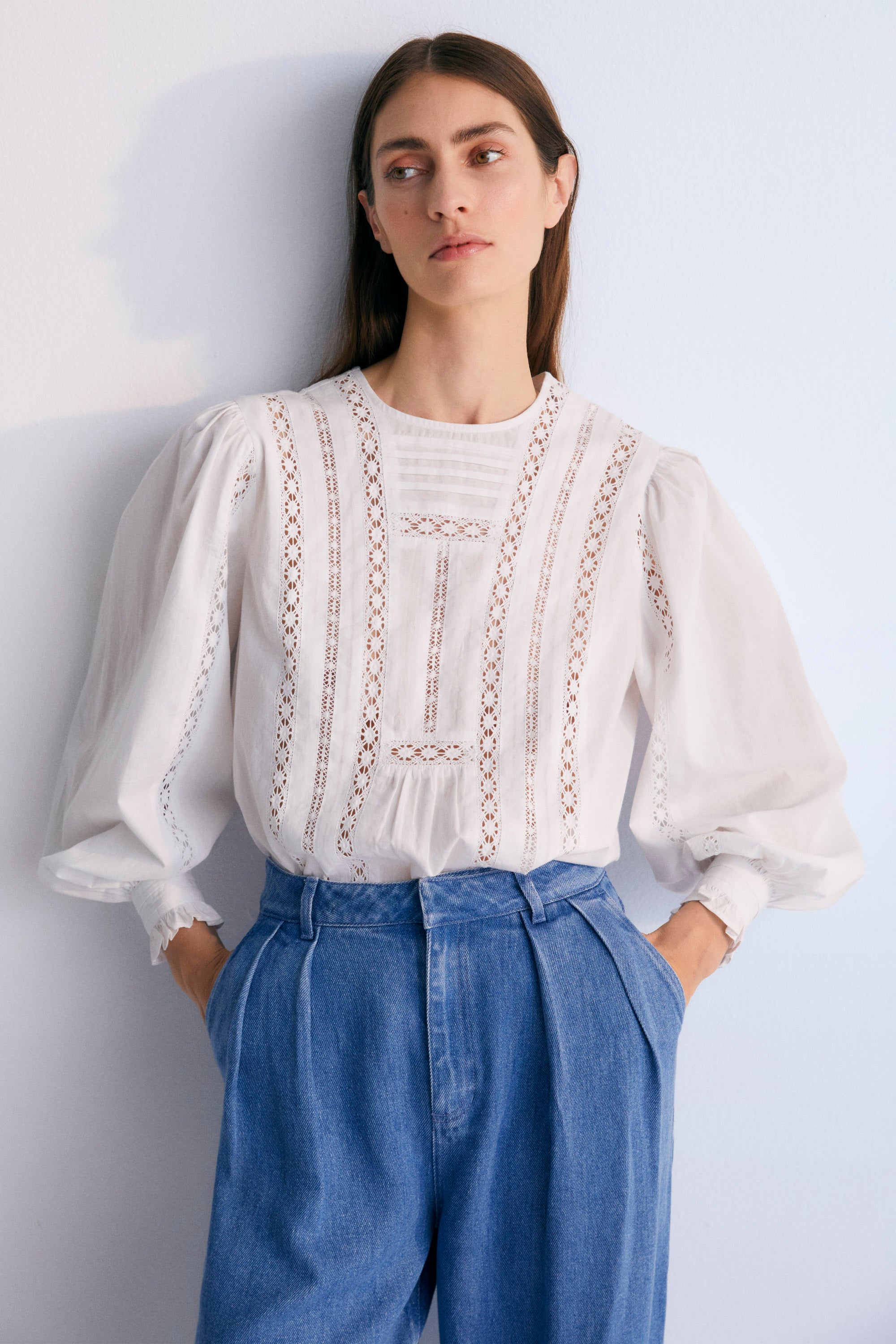 Romantic-style blouse with lace details on the front and back, long puffed sleeves, delicate cuff accents, and a back opening with mother-of-pearl buttons.